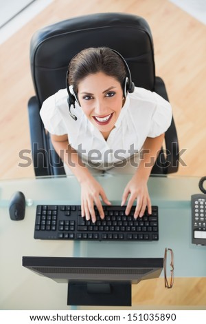 Happy call center agent typing while on a call in her workplace