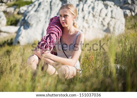 Woman with climbing equipment crouching down looking away