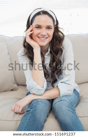 Peaceful casual woman sitting on a cosy couch in bright living room