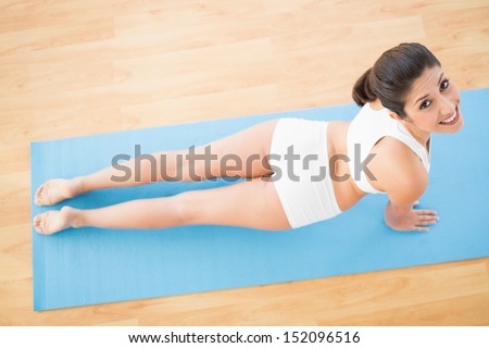Fit woman stretching in cobra pose at home on wooden floor