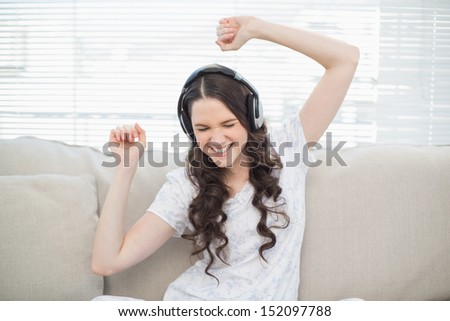 Pretty young woman dancing while listening to music in bright living room
