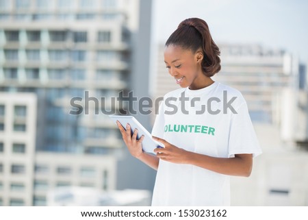 Woman wearing volunteer tshirt using tablet pc outdoors on urban background