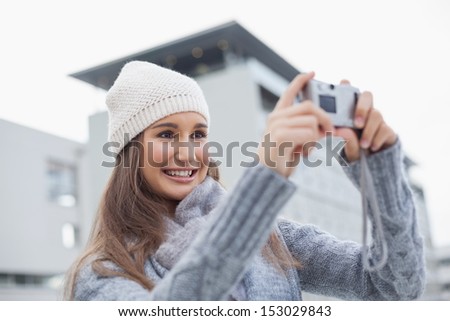 Smiling gorgeous woman with winter clothes on taking a self picture outdoors on a cold grey day