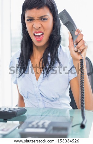 Exasperated businesswoman hanging up the phone in office