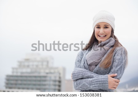 Cold cute brunette with winter clothes on posing outdoors on a cold grey day