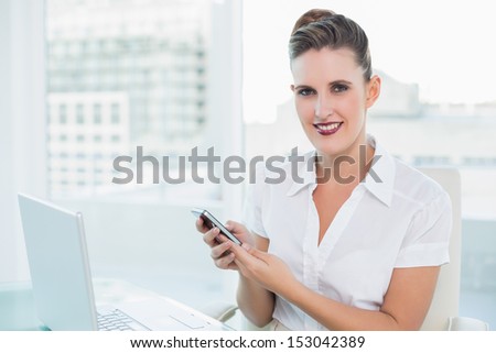 Cheerful gorgeous businesswoman using phone in bright office