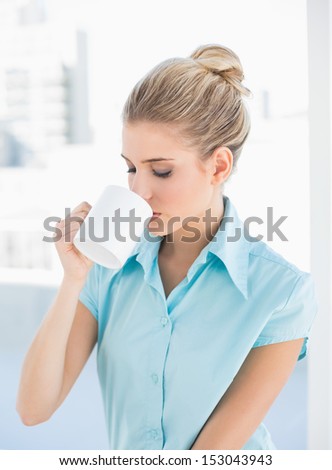 Peaceful elegant woman drinking coffee in bright office