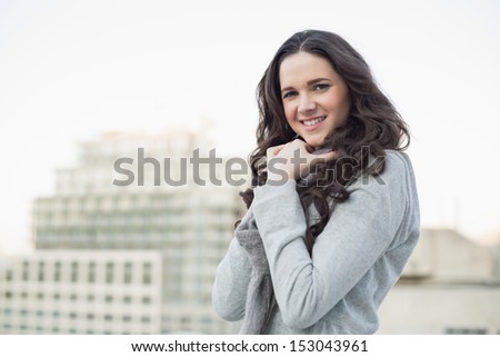 Smiling pretty brunette in winter clothes posing outside on a cloudy day