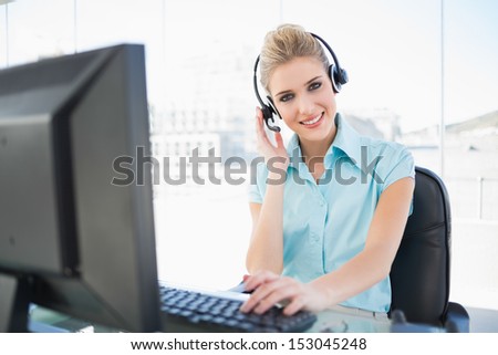 Happy call center agent working on computer in bright office