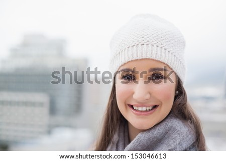 Smiling cute woman with winter clothes on posing outdoors on a cold grey day