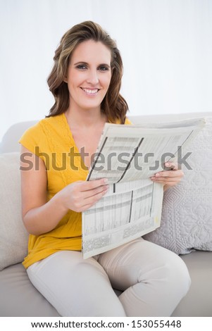 Smiling woman holding newspaper sitting on sofa