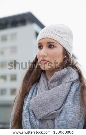 Thoughtful gorgeous woman with winter clothes on posing outdoors on a cold grey day