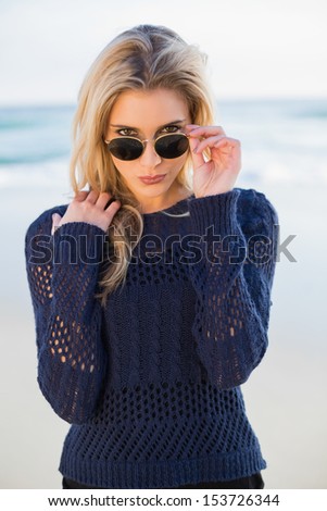 Gorgeous casual blonde on a beautiful wild beach looking over her sunglasses