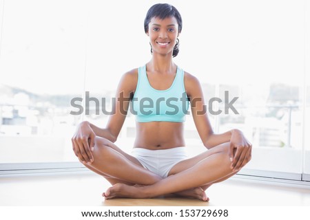 Smiling black haired woman doing yoga in a living room