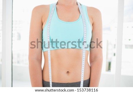 Woman in sportswear holding measuring tape in bright fitness studio