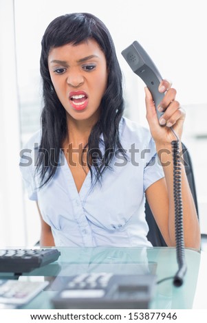 Angry businesswoman hanging up the phone in office