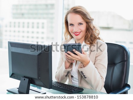Calm pretty businesswoman using a calculator at office
