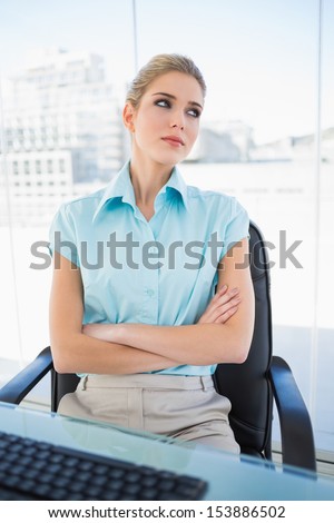 Thoughtful classy businesswoman in bright office crossing arms