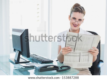 Smiling businesswoman holding newspaper looking at camera
