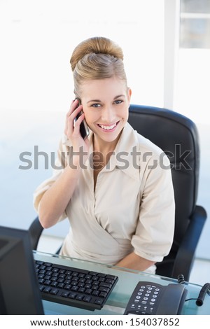 Cheerful young blonde businesswoman calling with her mobile phone at office