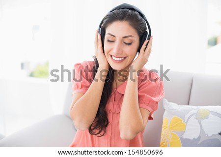 Calm brunette sitting on her sofa listening to music at home in the sitting room