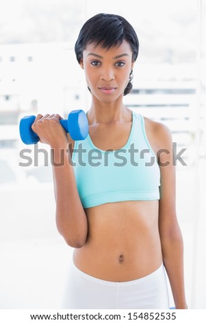 Stern black haired woman holding a dumbbell in a living room
