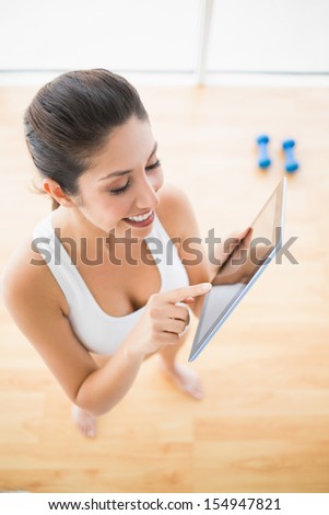 Fit woman using tablet taking a break from workout at home in bright room