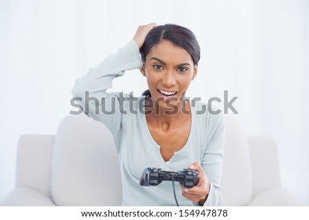 Irritated woman sitting on sofa in bright living room playing video games