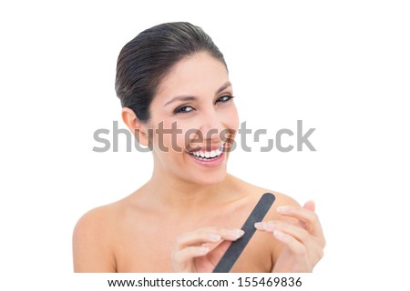Pretty brunette filling her nails and smiling at camera on white background