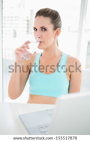 Fit woman in sportswear drinking water looking at camera