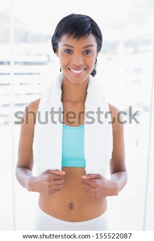 Smiling black haired woman wearing a towel around her neck in a living room