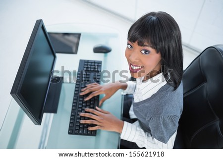High angle view of smiling pretty businesswoman in bright office typing