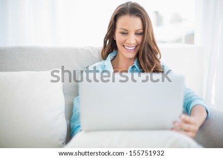 Happy pretty woman using laptop sitting on cosy sofa