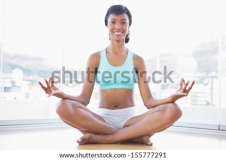 Cheerful black haired woman doing yoga in a living room
