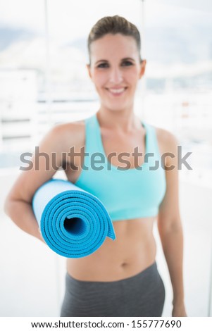 Young woman holding her fitness mat in bright fitness studio