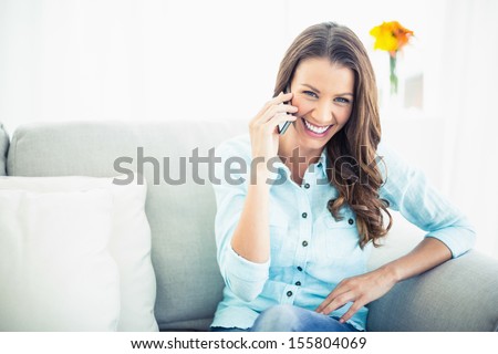 Attractive Model Sitting On Cosy Couch In Bright Living Room Having A Phone Call