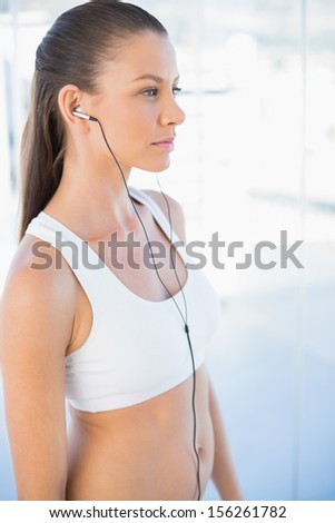 Woman in sportswear listening to music in bright fitness studio