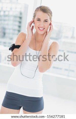 Cheerful sporty woman in bright sports hall listening to music