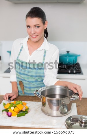 Smiling pretty woman wearing apron posing in bright kitchen