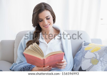 Peaceful Casual Brown Haired Woman In White Pajamas Reading A Book In A Bright Living Room