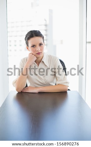 Irritated stylish brunette businesswoman posing looking at camera in bright office