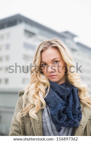 Unsmiling attractive blonde posing outdoors on urban background