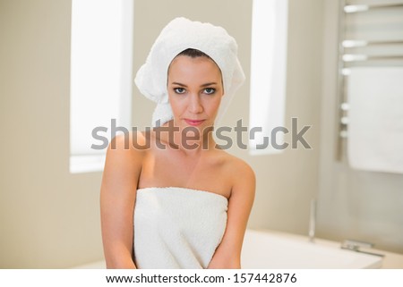 Stern natural brown haired woman preparing for her shower in a bright bathroom