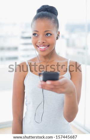 Cheerful gorgeous model in sportswear listening to music in bright room