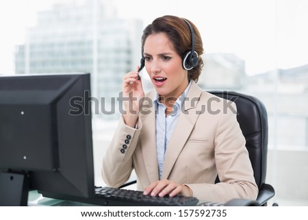 Angry businesswoman shouting in headset in bright office