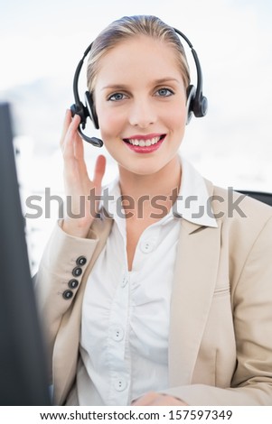 Smiling blonde call center agent interacting with customer in bright office