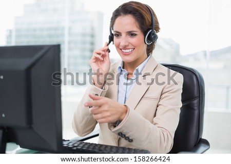 Smiling businesswoman pointing at computer in bright office