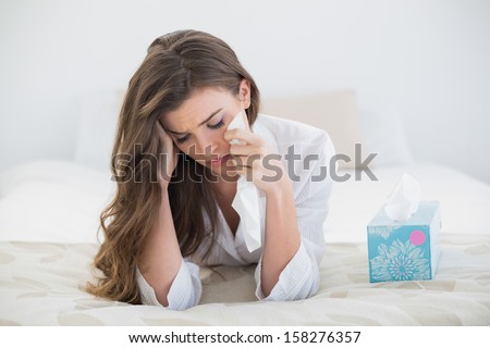 Depressed Casual Brown Haired Woman In White Pajamas Crying On Her Bed In A Bright Bedroom