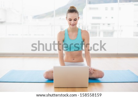 Sporty smiling woman using laptop in bright room