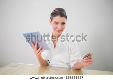 Cheerful pretty businesswoman shopping online in bright office